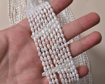 Könnte beinhalten: Nahaufnahme von mehreren Strängen weißer, oval geformter Perlen. Die Perlen sind aneinandergereiht und erzeugen einen Kaskadeneffekt. Das Bild hebt den Glanz und die Form der Perlen hervor und deutet auf ihre Verwendung in Schmuck oder Kunsthandwerk hin.