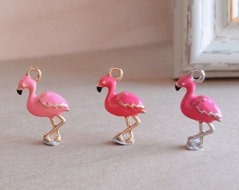 May include: Three pink flamingo charms with gold accents. The charms are made of metal and have a shiny finish.