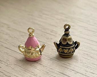 May include: Two gold teapot charms, one with pink enamel and the other with a brown finish. Both charms have a heart design.