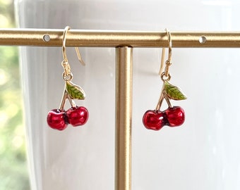May include: Gold cherry earrings with red enamel cherries and green enamel leaves.