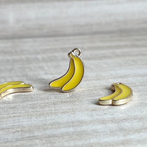 May include: Three yellow metal banana charms with silver accents. The charms are ideal for adding a fun and quirky touch to jewellery, keyrings, or other crafts.