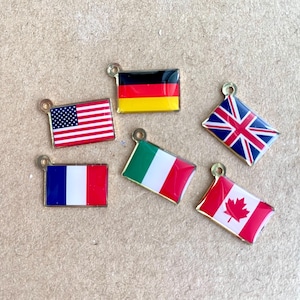 May include: Six small metal charms shaped like flags. The flags are of the United States, Germany, United Kingdom, France, Italy, and Canada.