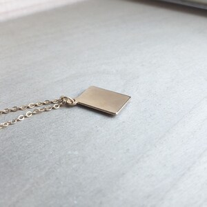 May include: A gold chain necklace with a small, rectangular pendant.