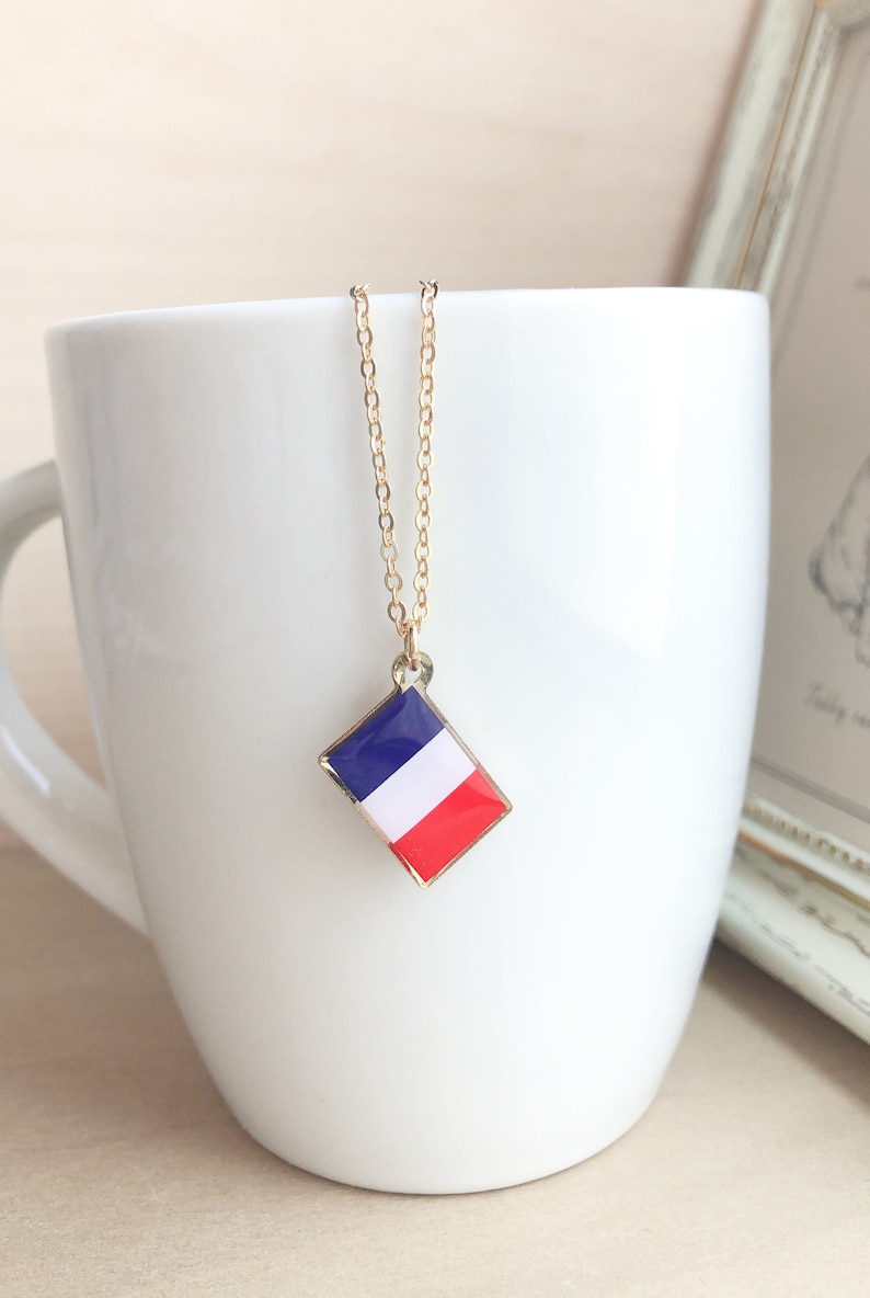 May include: A gold chain necklace with a diamond-shaped pendant featuring the French flag colors: blue, white, and red.