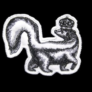 May include: A black and white embroidered patch of a skunk wearing a crown. The skunk is facing right and has a long, bushy tail.