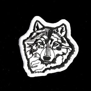 May include: Black and white embroidered patch of a wolf's head. The wolf's fur is detailed with black stitching and the eyes are outlined in black.