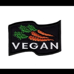 May include: Black and white embroidered patch with a waving flag design. The flag features three orange carrots with green tops and the word "VEGAN" in white letters.