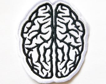 May include: An embroidered patch featuring a stylised human brain design. The patch has a white background with thick, black thread stitching forming the intricate, branching sulci and gyri patterns of the brain, finished with a white border.