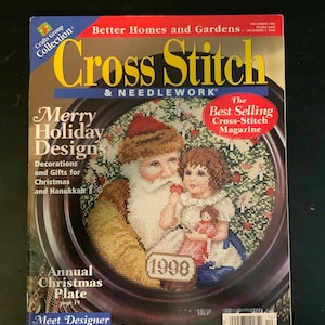 May include: A magazine cover for "Cross Stitch & Needlework" featuring a cross-stitch design of Santa Claus and a child. The cover includes the text "Merry Holiday Designs" and "Annual Christmas Plate". The magazine is from December 1998.