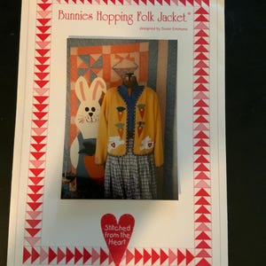 May include: A photograph of a pattern for a folk jacket. The jacket is yellow with carrot and bunny appliqués. The pattern is titled "Bunnies Hopping Folk Jacket" and includes the phrase "Stitched from the Heart."
