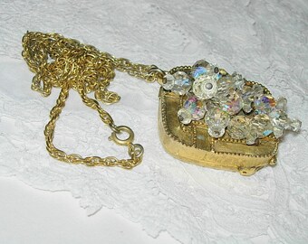 May include: A gold chain necklace with a gold pendant featuring a cluster of clear iridescent crystals.