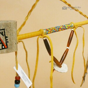 Peut inclure: Une pipe cérémonielle amérindienne avec un bol en bois, un manche perlé et des glands en cuir. Le bol est peint avec un motif géométrique en noir, rouge et blanc. Le manche est enveloppé de cuir et décoré de perles colorées. Les glands sont en cuir et sont attachés au manche avec des cordons en cuir.