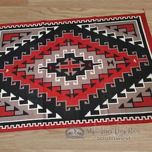 Peut inclure: Un tapis géométrique rouge, noir, blanc et gris avec un motif sud-ouest. Le tapis a une bordure rouge et noire.