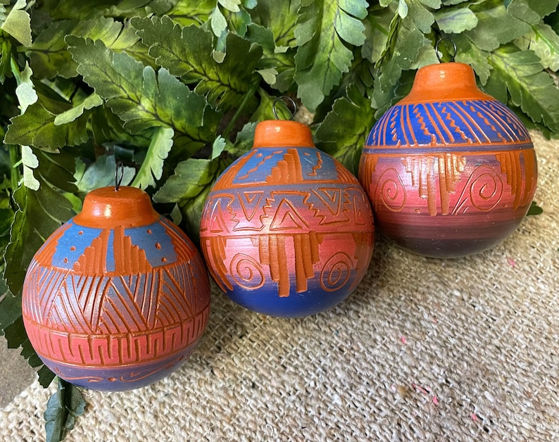 Peut inclure: Trois ornements en c&eacute;ramique faits &agrave; la main avec des motifs d'inspiration sud-ouest. Les ornements sont peints dans des tons de bleu, rouge et orange avec des motifs g&eacute;om&eacute;triques complexes.