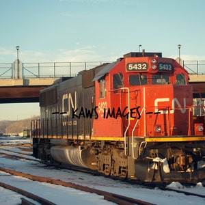 May include: A red and black Canadian National Railway locomotive with the number 5432 on the side, parked on a snowy track.