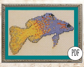 Può includere: Opera d'arte a punto croce di un pesce in una cornice argentata. Il pesce è principalmente giallo e viola, con accenti arancioni e perline dorate. L'opera è su uno sfondo beige, con un bordo turchese. L'angolo in basso a destra ha le lettere "PDF".