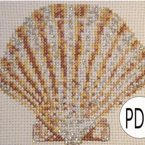 May include: A cross-stitch pattern of a seashell with a beige background. The shell is made of brown, yellow, and silver thread. The pattern is labeled "PDF".