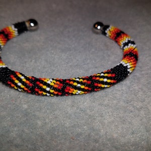 Beaded bangle bracelet, Black with fire colored geometric patterns