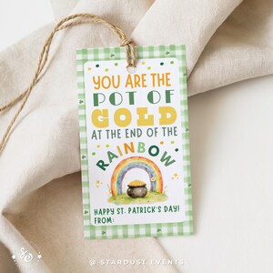 May include: A St. Patrick's Day gift tag with a green and white gingham pattern. The tag features the text "YOU ARE THE POT OF GOLD AT THE END OF THE RAINBOW" with a rainbow and pot of gold illustration. A twine string is attached.