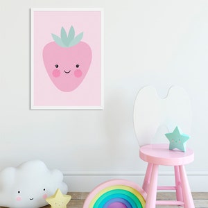 May include: A pink framed print of a cartoon strawberry with a smiling face on a pink background. A pink wooden stool with a white bunny ear back, a rainbow arch, a white cloud nightlight, and a yellow star nightlight are in the foreground.