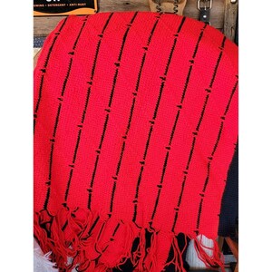 Peut inclure: Jeté de canapé en crochet rayé rouge et noir avec des franges.