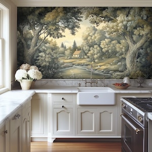 May include: A white farmhouse kitchen with a large mural of a forest scene with a river and a small cottage. The mural is above a white farmhouse sink with a brass faucet. The kitchen has white cabinets and a black stove.