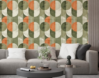 May include: A mid-century modern wallpaper design featuring a repeating pattern of half-circles in shades of olive green, orange, and cream. The wallpaper is installed behind a gray sofa with white and black pillows, and a dark gray coffee table.