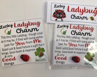 May include: Two white cards with a red ladybug charm and green four-leaf clover. The cards have the text "Lucky Ladybug Charm" and a message about good luck and good fortune.