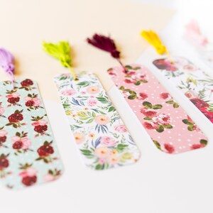 Peut inclure: Cinq marque-pages &agrave; motifs floraux avec des accents de pompons. Les marque-pages pr&eacute;sentent diff&eacute;rents motifs floraux dans des tons de rose, rouge, vert et blanc. Les pompons sont dans des tons de violet, vert, marron, jaune et blanc.