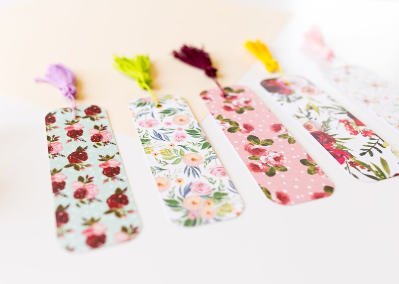 Peut inclure: Cinq marque-pages &agrave; motifs floraux avec des accents de pompons. Les marque-pages pr&eacute;sentent diff&eacute;rents motifs floraux dans des tons de rose, rouge, vert et blanc. Les pompons sont dans des tons de violet, vert, marron, jaune et blanc.