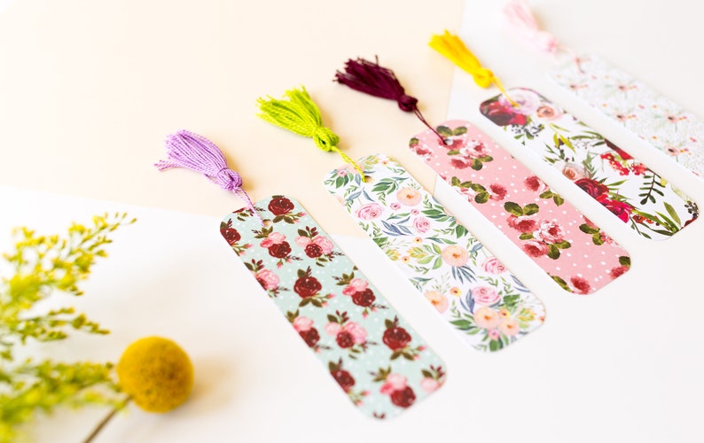 Peut inclure: Cinq marque-pages &agrave; motifs floraux avec des accents de pompons. Les marque-pages pr&eacute;sentent diff&eacute;rents motifs floraux dans des tons de rose, rouge et vert. Les pompons sont dans des tons de violet, jaune et vert.