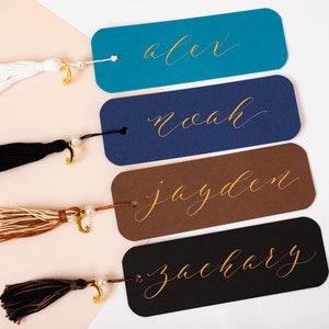 May include: Four personalised bookmarks with gold lettering and tassels. The names on the bookmarks are Alex, Noah, Jayden, and Zachary.