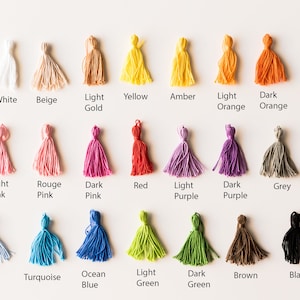 May include: A color chart of 18 different colors of yarn with tassels. The colors include white, beige, light gold, yellow, amber, light orange, dark orange, light pink, rouge pink, dark pink, red, light purple, dark purple, grey, light blue, turquoise, ocean blue, light green, dark green, brown, and black.
