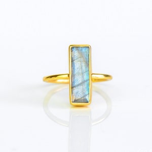 May include: A gold ring with a rectangular iridescent blue labradorite gemstone.