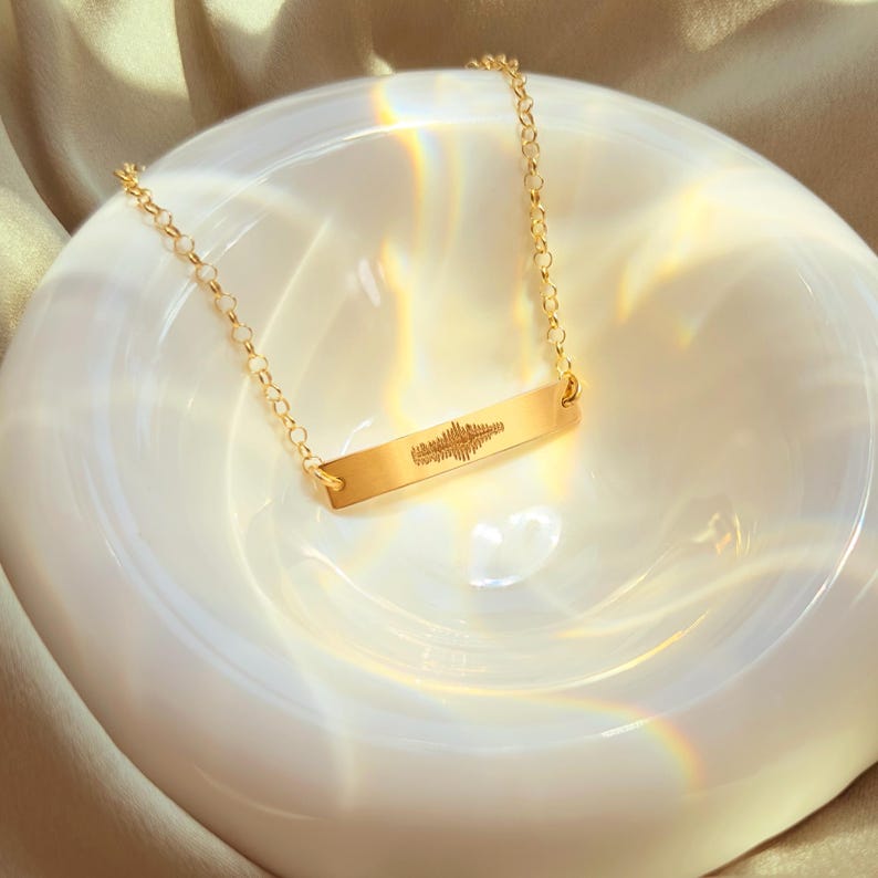 Golden heartbeat bar necklace on satin with prism glow; personalized ultrasound soundwave engraving, option to add name and birth date on reverse; fine 14k gold filled chain, minimalist layering necklace; pregnancy reveal, new mama gift, push present.