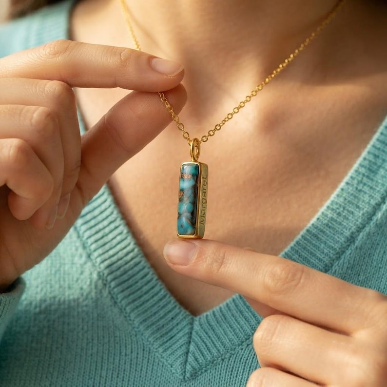 Close-up of December birthstone bar necklace showing turquoise stone, gold setting, and delicate chain.