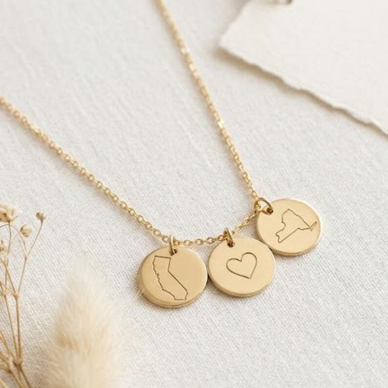 Close-up of custom two state necklace with engraved location discs and center heart charm.