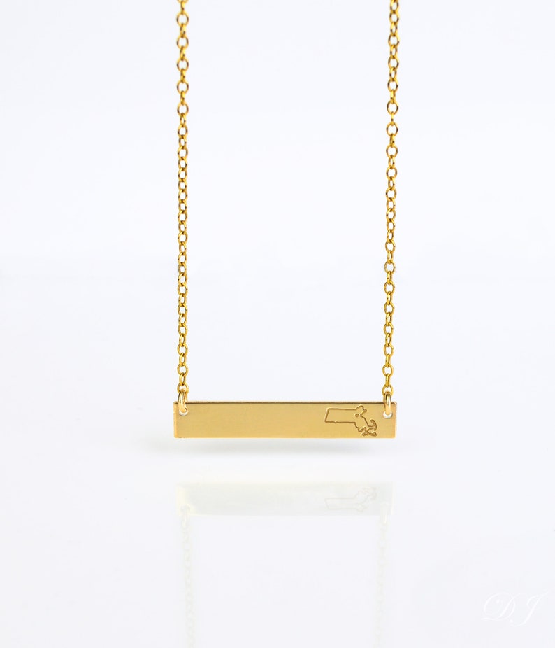May include: Gold necklace with a bar pendant featuring an outline of the state of Massachusetts.