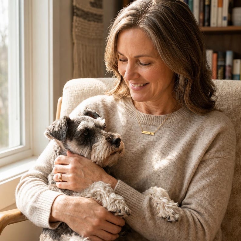 Woman wearing custom paw print bar necklace while holding her dog, a personalized pet memorial necklace with name engraving.