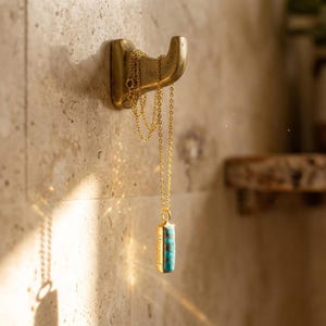 Personalized December birthstone necklace with turquoise gemstone and hidden engraving, shown hanging in soft sunlight.
