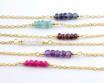 Puede incluir: Cinco pulseras de cadena dorada con cuentas de piedras preciosas de diferentes colores. Las pulseras presentan cuentas de aguamarina, blancas, amatistas y rosas.