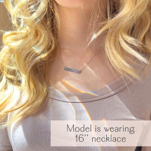 Model wearing dainty silver heartbeat bar necklace engraved with baby’s heartbeat design, rainbow light reflecting on fabric. Personalized keepsake jewelry gift for moms, pregnancy announcement, miscarriage memorial, or baby shower present.