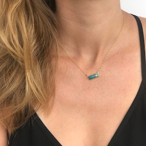 A person in a black v neck shirt wears a copper turquoise bar necklace set in silver. Turquoise necklace, natural turquoise necklace, copper turquoise necklace, handmade jewelry, handmade turquoise necklace, december birthstone jewelry