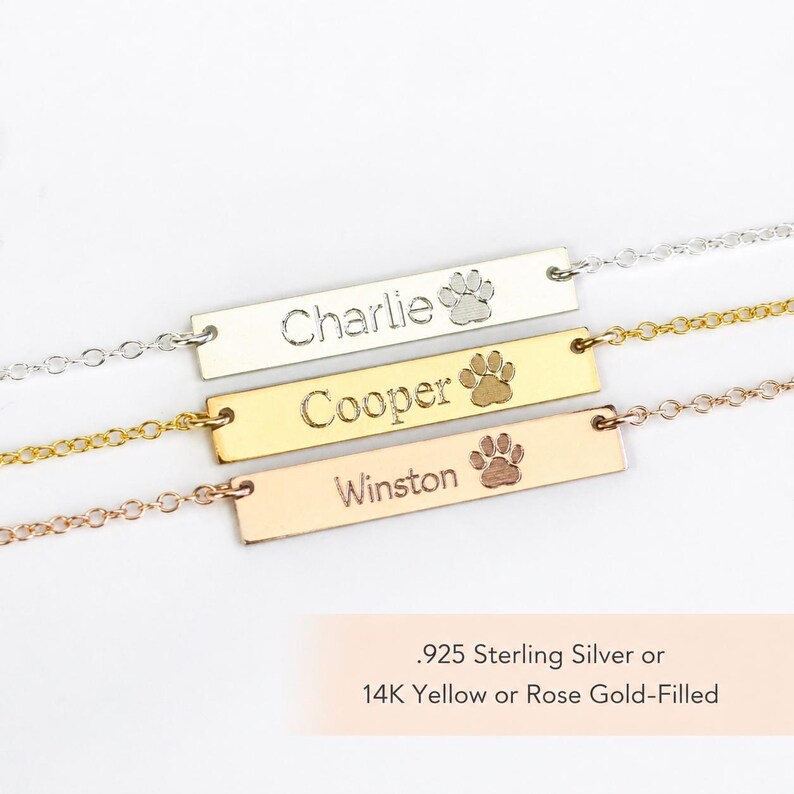 Paw print bar necklaces shown in sterling silver, yellow gold filled, and rose gold filled with custom pet name engraving.