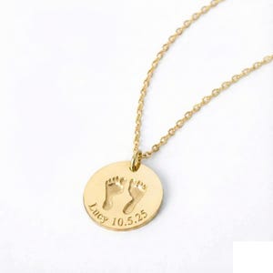 Gold baby footprint necklace featuring a round engraved pendant with tiny footprints, personalized name, and birthdate. Shown on a white background to highlight the delicate chain and custom engraving, perfect for new moms and keepsake gifts