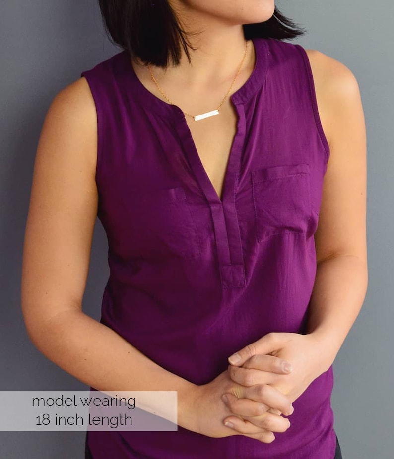 May include: A model wearing a purple sleeveless top with a gold bar necklace. The necklace is 18 inches long.  model wearing 18 inch length