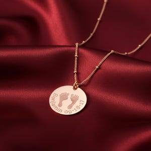 Round engraved baby footprint necklace featuring tiny footprints and optional name or birthdate. A sweet and meaningful new mom gift, this personalized pendant makes a beautiful keepsake to celebrate a baby’s first moments and cherish every milestone.