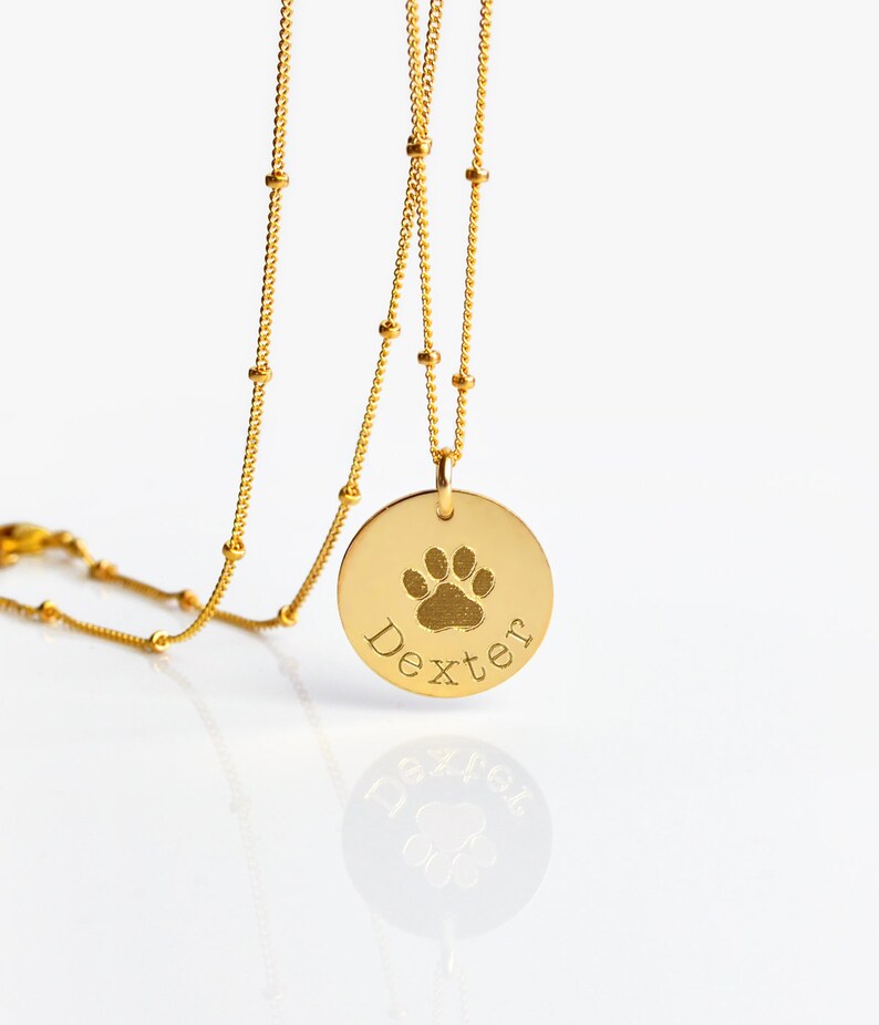 If you would like to use a custom image of your pet's pawprint, please choose one of the CUSTOM options from the first menu. Disc charm is 16 mm/ 0.5 in
Model is wearing 18 in length with gold satellite chain. name charm necklace, name necklace