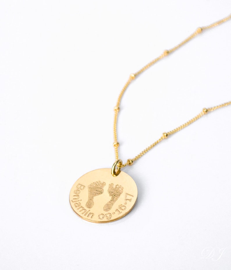 A gold baby footprint disc necklace sits against a white background. Actual baby portrait jewelry, actual baby footprints, baby handprint necklace, baby keepsake jewelry for new mom, loss of baby memorial jewelry for mother, first mothers day gift