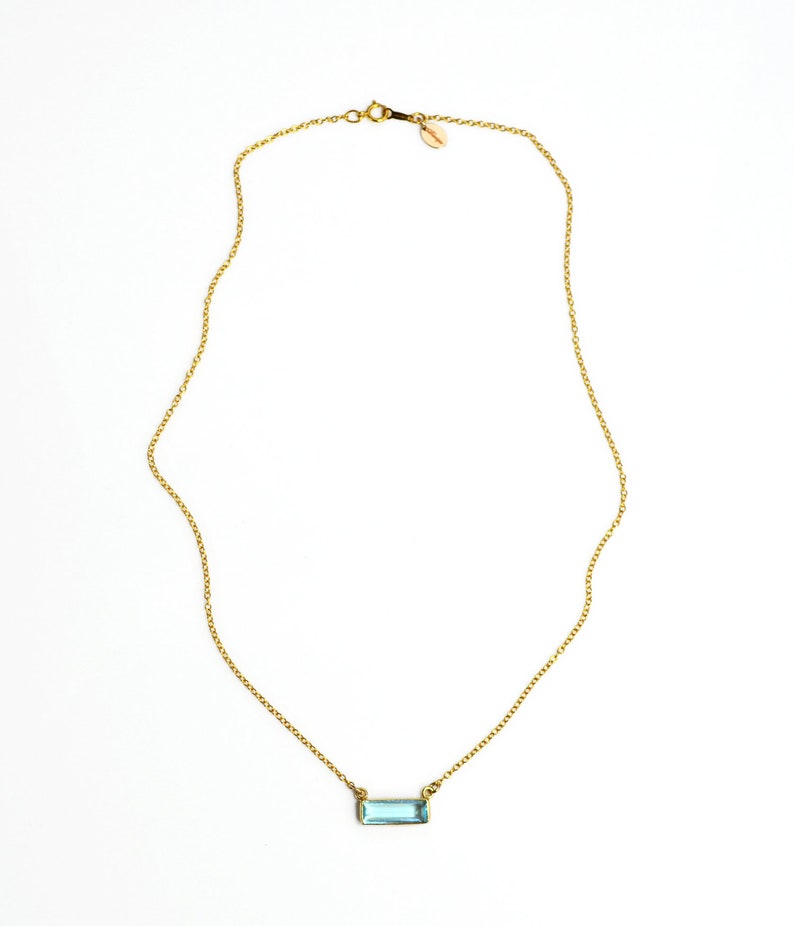 A gold blue topaz adira bar necklace on a cable chain. Blue necklace, blue stone necklace, december birthstone jewelry for new mom, baby birthstone jewelry, light blue gemstone necklace, gemstone necklaces, winter fashion jewelry, jewelry for winter